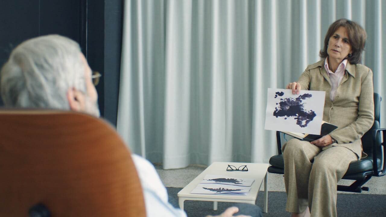 A psychologist and client sitting together completing a worksheet collaboratively, warm clinical office setting